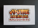 A white rectangular card or sticker featuring the stylized text 'ANIME LEGENDS MASTERPIECES' in orange, yellow, and red gradient lettering with a white border, photographed against a dark gray background.