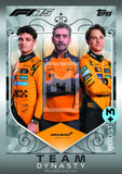 Three Formula 1 drivers in orange racing suits with McLaren branding on a decorative card background.